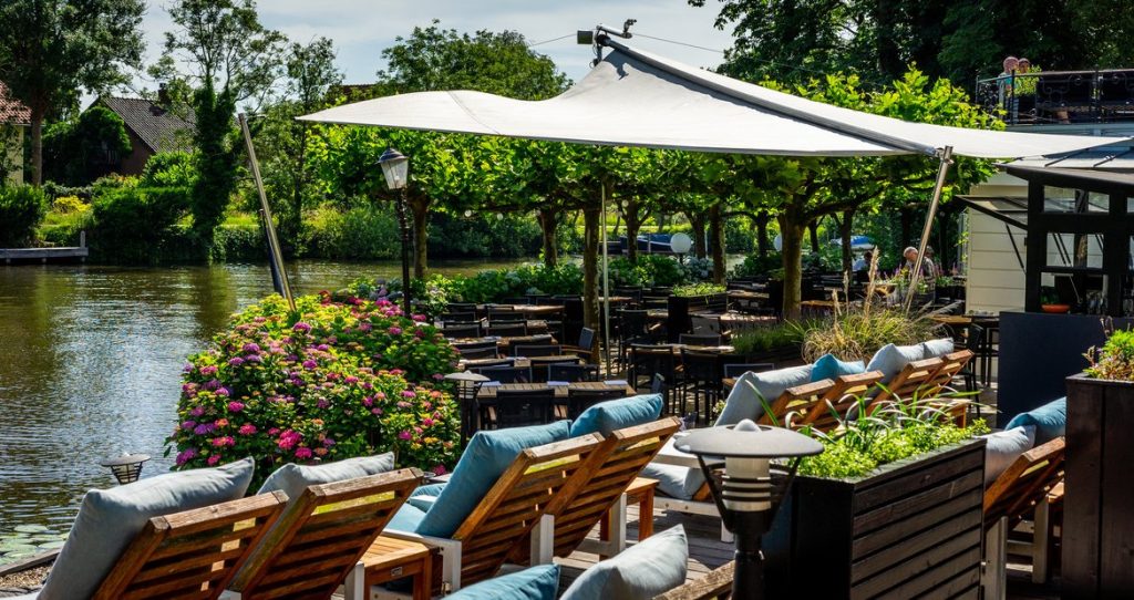 Zonnig terras aan het water met comfortabele loungestoelen bij Slangevegt Breukelen