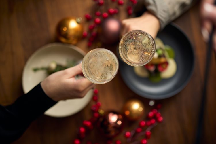 twee mensen proosten met champagneglazen boven een kerstdiner